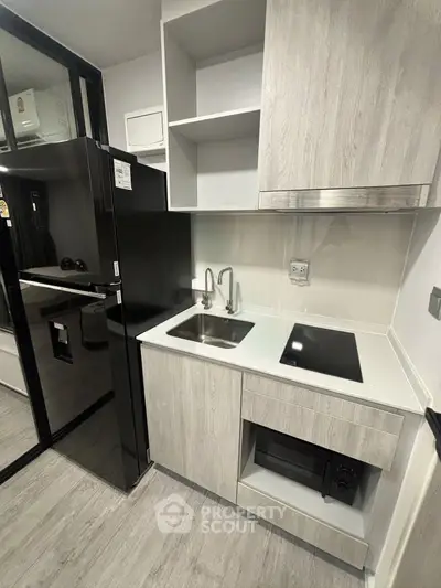 Modern compact kitchen with sleek cabinetry and built-in appliances in a stylish apartment.