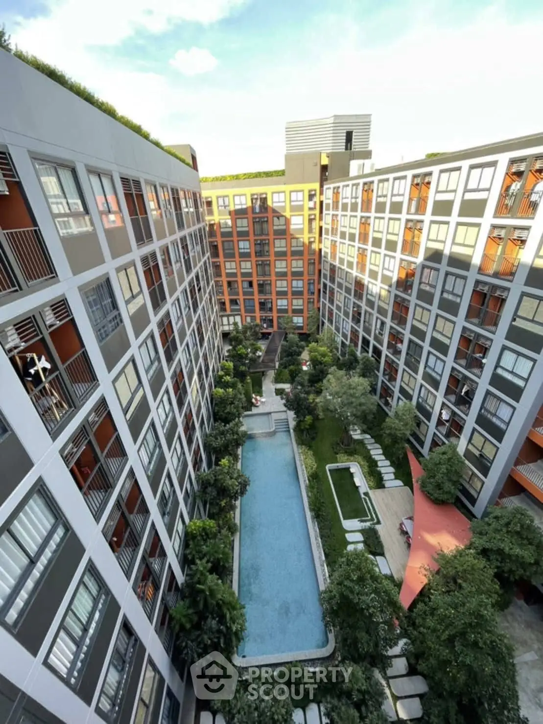 Modern apartment complex with central pool and lush greenery