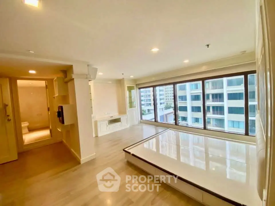 Spacious modern living room with large windows offering stunning city views in a luxury apartment.