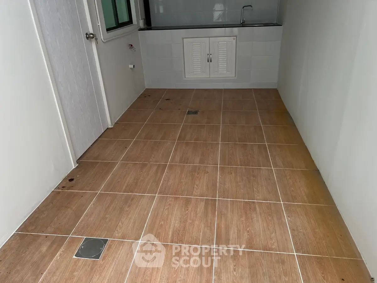 Spacious tiled room with sink and storage, ideal for utility or laundry use.