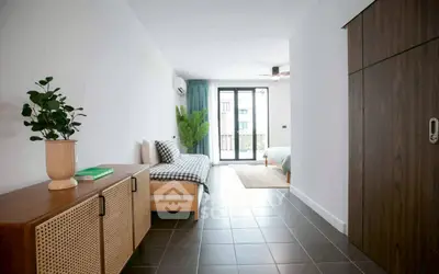 Modern studio apartment with stylish decor and natural light, featuring a cozy bed and sleek furniture.