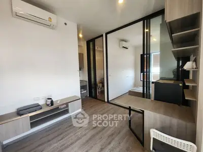 Modern studio apartment with sleek design and wooden flooring, featuring a compact workspace and air conditioning.