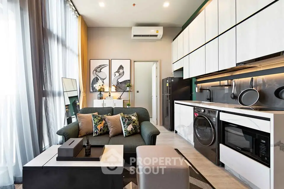 Modern open-layout living room with kitchen, featuring stylish decor and natural light.