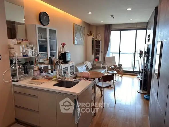 Modern open-layout living room with kitchen, featuring sleek design and natural light.