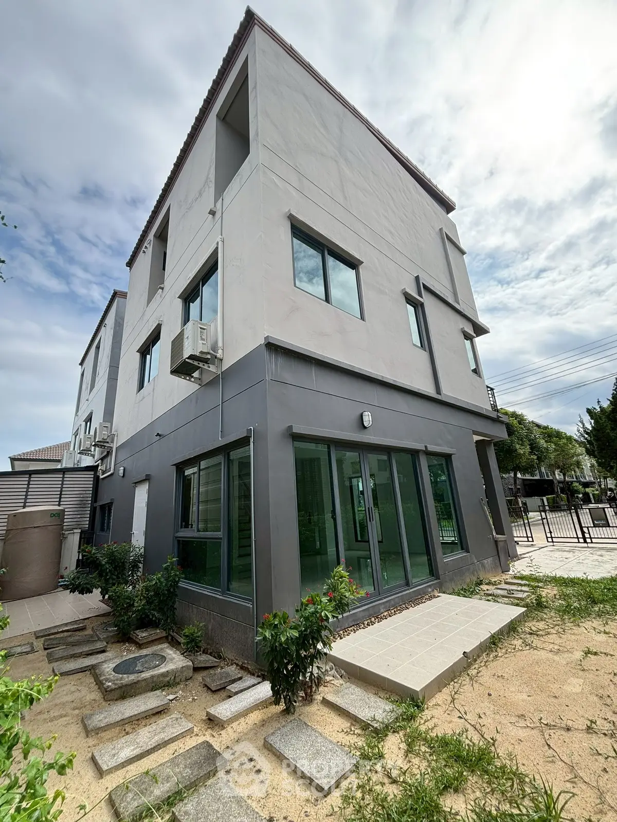 Modern three-story building with landscaped garden and large windows