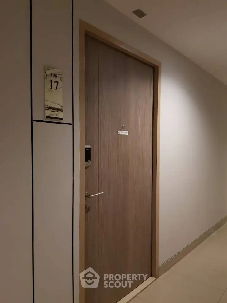 Modern apartment entrance with sleek wooden door and electronic lock system.