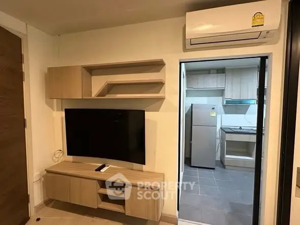 Modern living room with wall-mounted TV and view into sleek kitchen