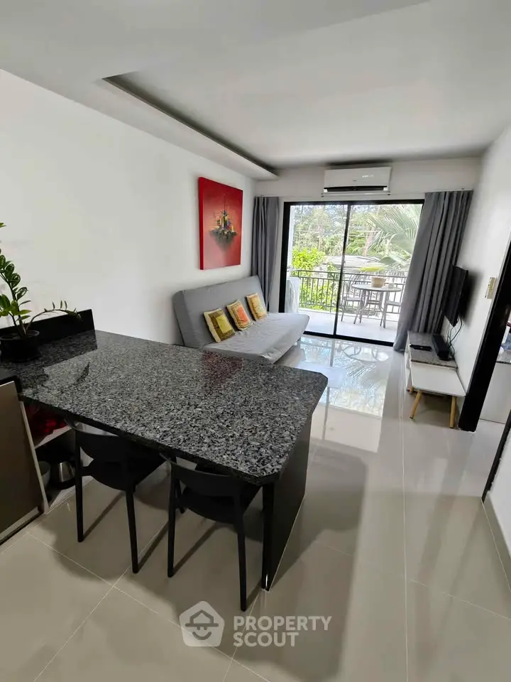 Modern living room with open layout and balcony view, featuring sleek furniture and natural light.