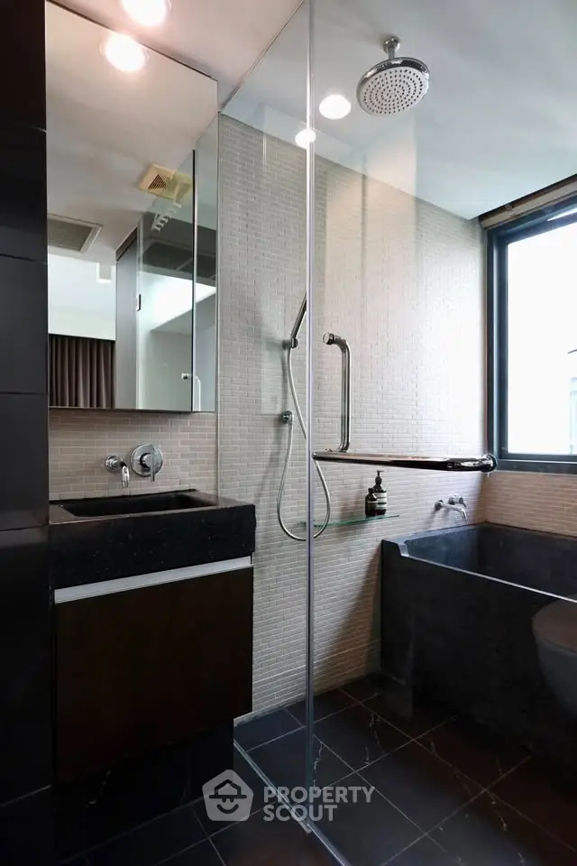 Modern bathroom with glass shower, black bathtub, and sleek fixtures