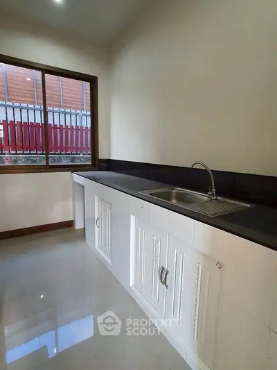 Modern kitchen with sleek countertops and large window for natural light.