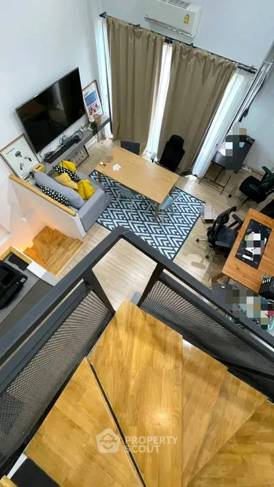 Modern loft-style living room with high ceiling, stylish decor, and wooden staircase.