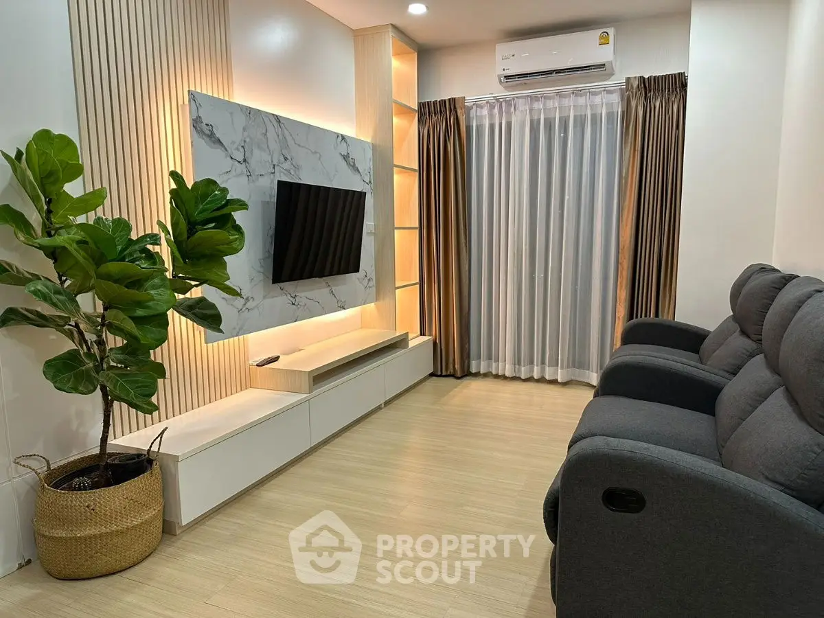 Modern living room with sleek TV setup and cozy seating, featuring elegant lighting and stylish decor.