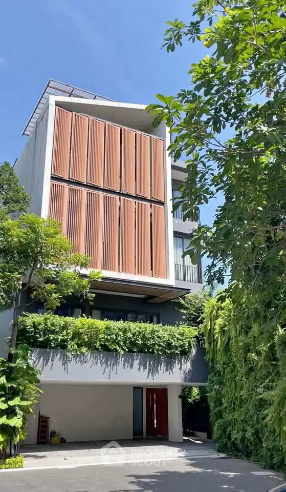 Modern architectural building with lush greenery and unique facade design.