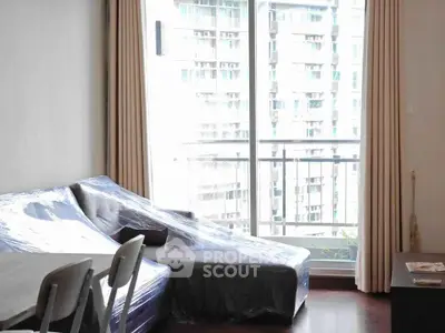 Modern living room with large window and city view, featuring a wrapped sofa and elegant curtains.