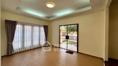 Spacious living room with large windows and garden view, perfect for natural light lovers.