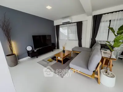Modern living room with stylish decor, featuring a large sectional sofa, flat-screen TV, and elegant curtains.