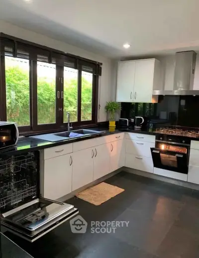 Modern kitchen with sleek appliances and large windows offering natural light.
