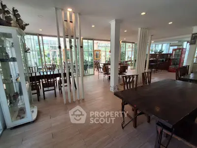 Spacious dining area with elegant wooden furniture and large windows offering garden views.