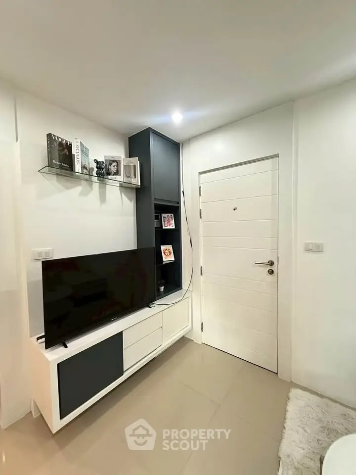 Modern living room with sleek TV unit and white door, showcasing minimalist design.