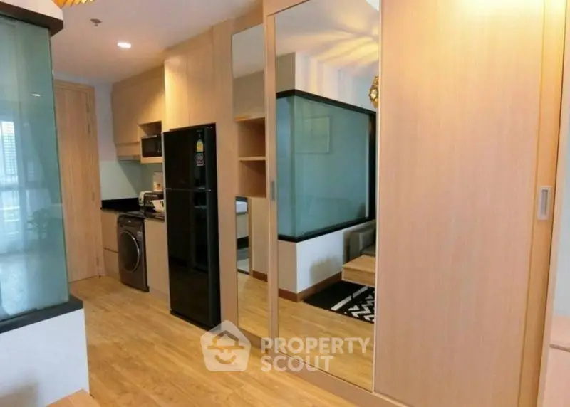 Modern apartment interior with mirrored wardrobe and sleek kitchen appliances