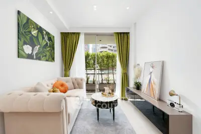 Stylish living room with elegant decor and lush green curtains opening to a balcony view.