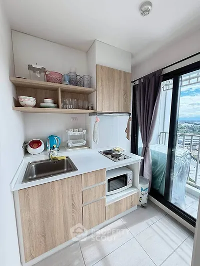 Modern compact kitchen with balcony view, featuring wooden cabinets and sleek appliances.