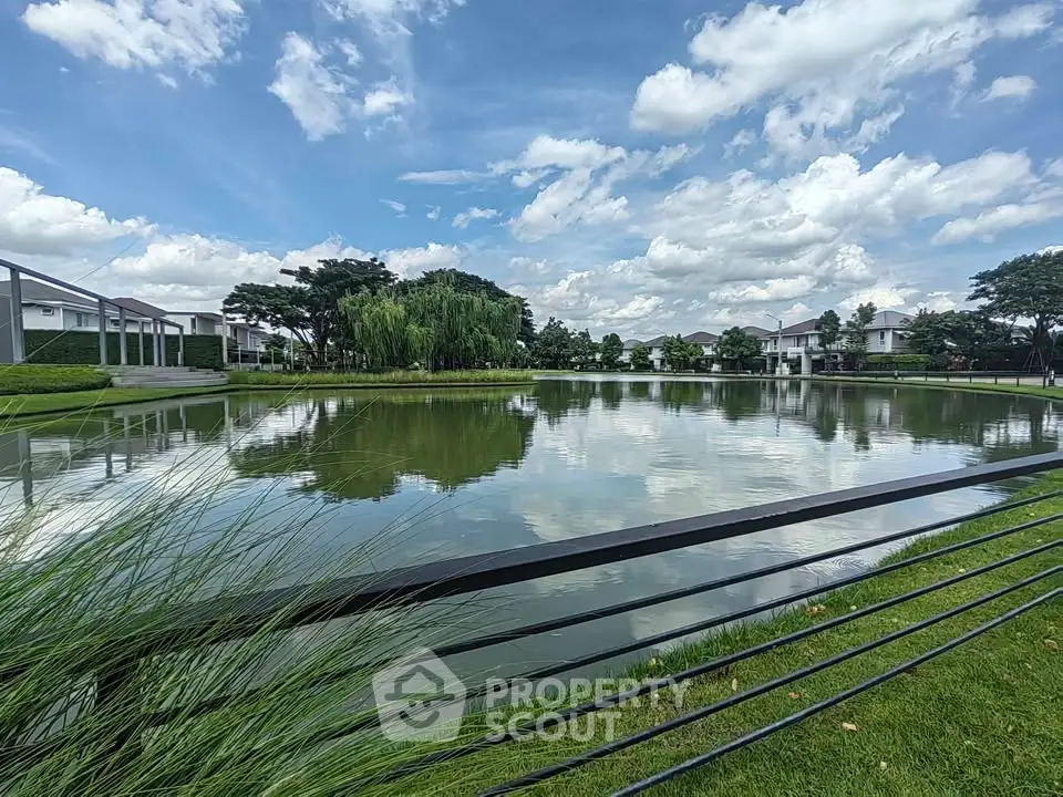 Stunning lakeside view with modern homes and lush greenery under a vibrant blue sky.