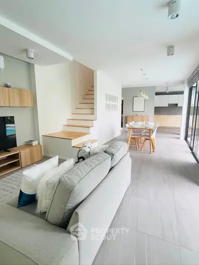 Modern open-plan living room with stylish staircase and dining area in a contemporary home.