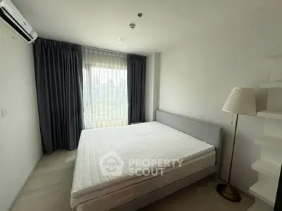 Spacious bedroom with large window and modern furnishings in a high-rise apartment.