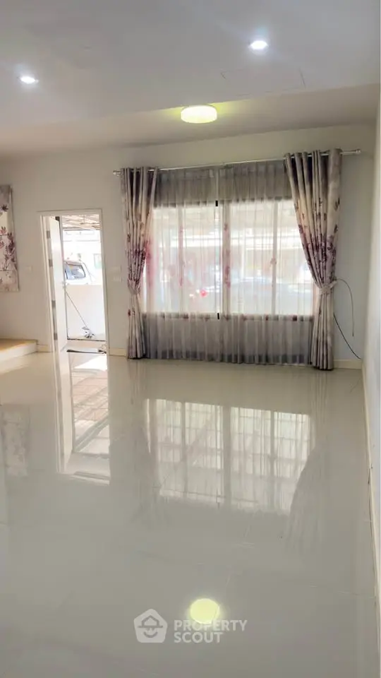 Spacious living room with large windows and elegant curtains, perfect for natural light and modern living.
