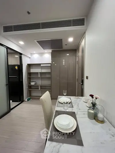 Modern dining area with sleek marble table and open kitchen layout in a stylish apartment.