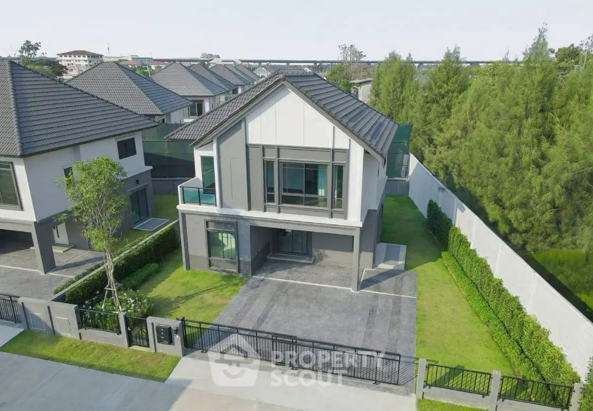 Modern two-story house with spacious driveway and lush green surroundings.