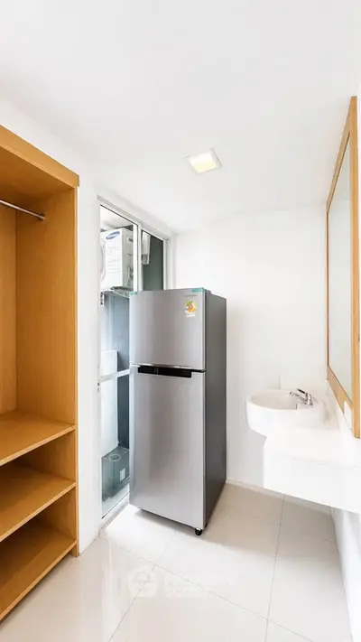 Modern utility room with sleek fridge and built-in storage in bright apartment.