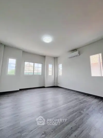 Spacious empty room with large windows and modern flooring, perfect for customization.