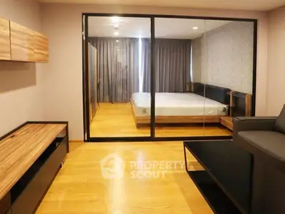 Modern bedroom with glass partition and wooden flooring in a stylish apartment.