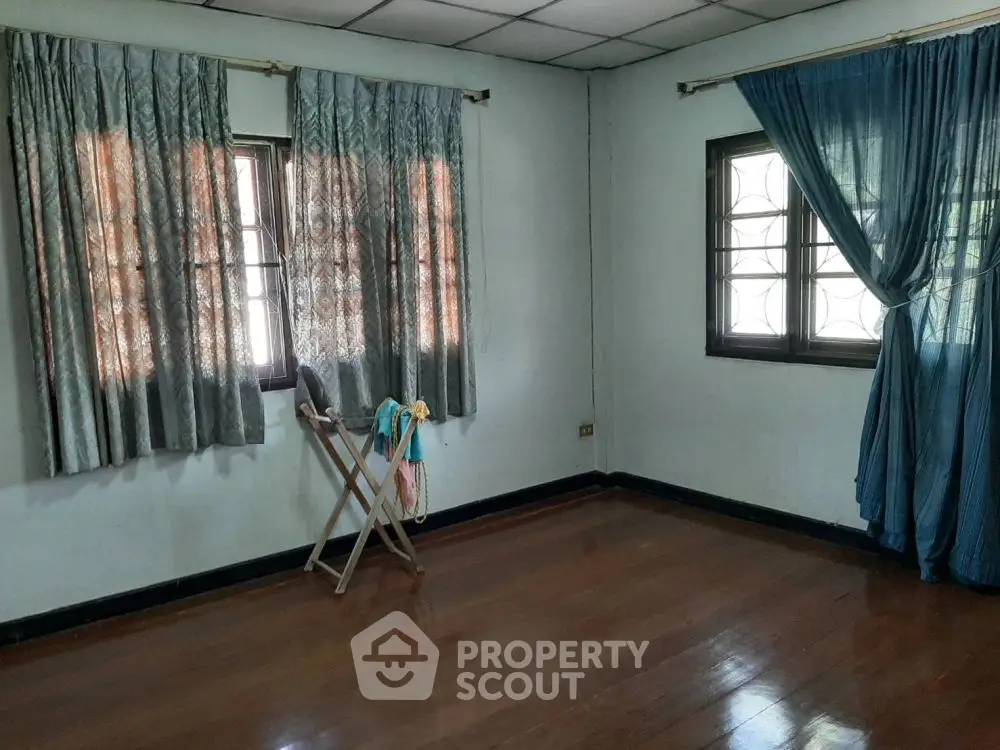 Spacious room with wooden flooring and large windows, ideal for customization.