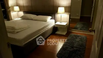 Cozy bedroom with elegant lighting and hardwood floors, featuring a plush bed and stylish decor.