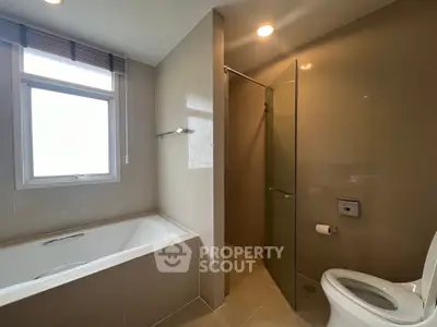 Modern bathroom with bathtub and glass-enclosed shower in a sleek design.