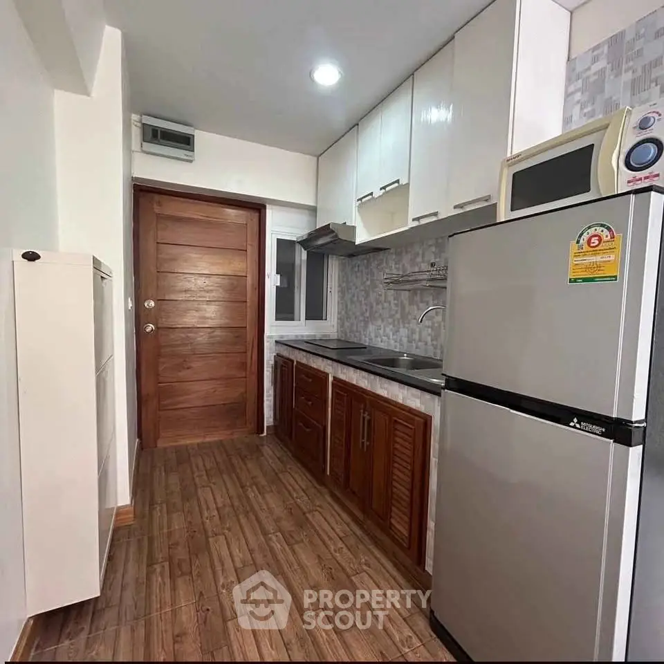 Modern kitchen with wooden cabinets and stainless steel appliances in a cozy apartment.