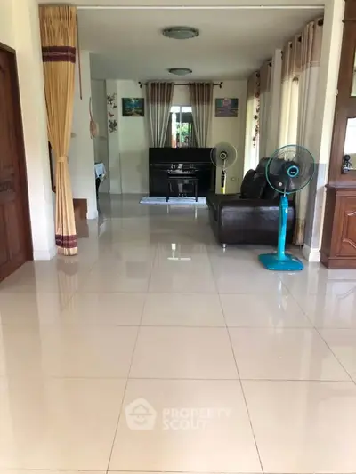 Spacious living room with tiled floors, elegant curtains, and modern furniture.
