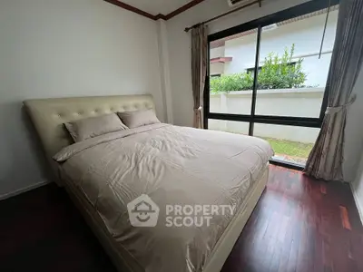 Cozy bedroom with large window and garden view, featuring a plush bed and elegant curtains.