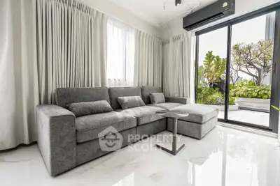 Modern living room with sleek gray sofa and garden view through sliding glass doors.