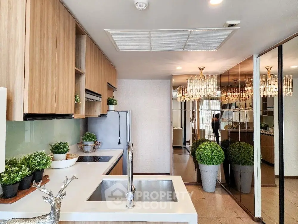 Modern kitchen with sleek design, mirrored walls, and elegant lighting fixtures.