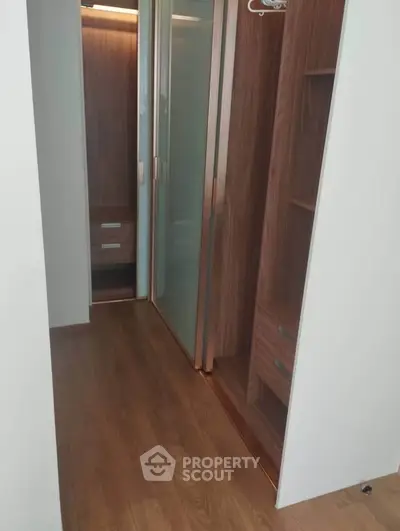 Spacious walk-in closet with wooden flooring and modern sliding doors.