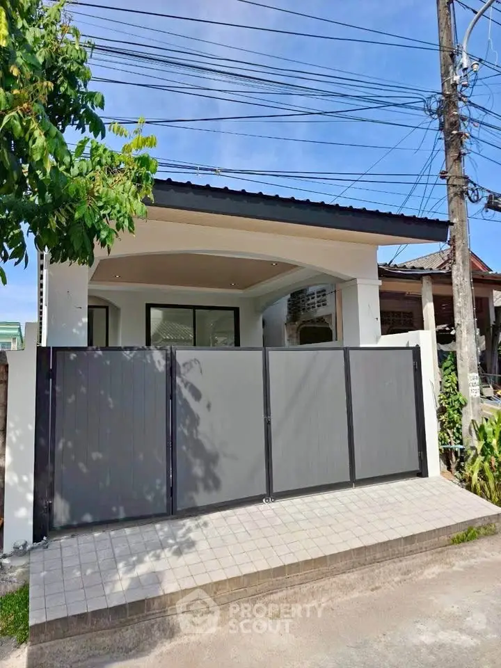 Modern single-story house with sleek gate and tiled entrance in a suburban neighborhood.
