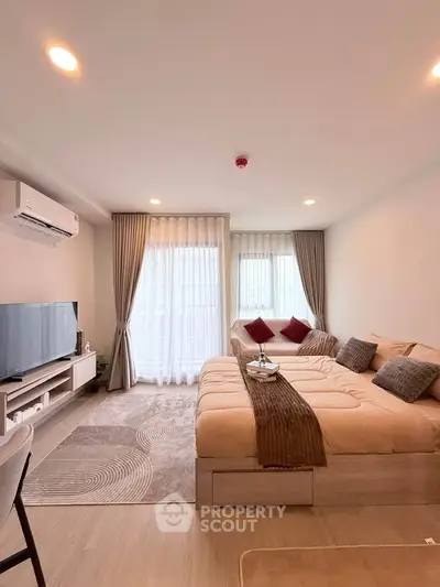 Modern living room with cozy sofa and large TV, featuring elegant curtains and stylish decor.