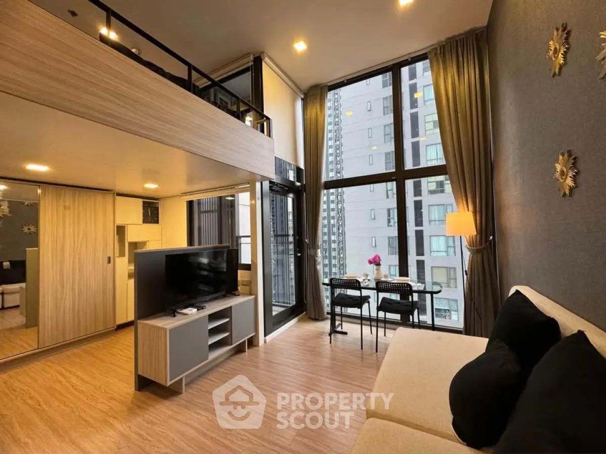 Modern loft apartment with high ceilings and large windows offering city views.