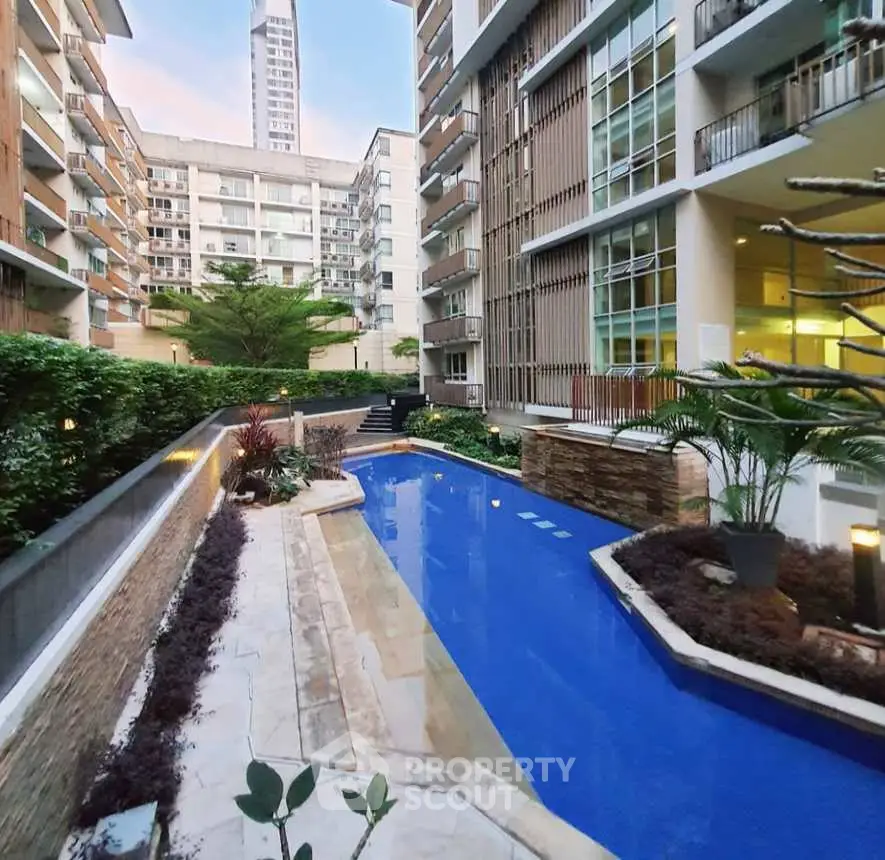 Luxurious apartment complex with modern pool and lush greenery, perfect for urban living.