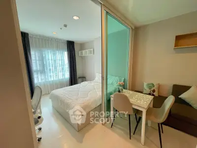 Modern bedroom with glass partition, cozy dining area, and natural light in a stylish apartment.