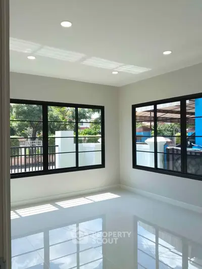 Bright and spacious living room with large windows and glossy tiled floor, offering a serene view.